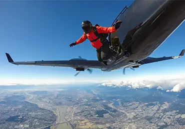 Skydiver jumping out of an airplane during a sunny summer day with City in the background