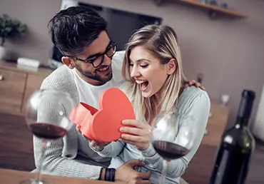 Couple celebrating Valentine's Day with wine and chocolate.