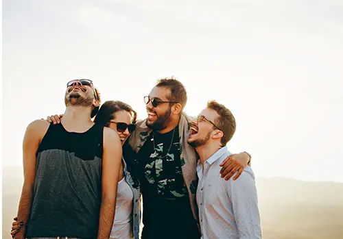 A group of smiling people enjoying each other’s company, representing the positive impact of healthy indulgences and social connection, vices for your health.