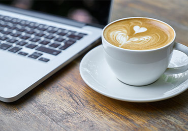 A cup of coffee sits near a computer.