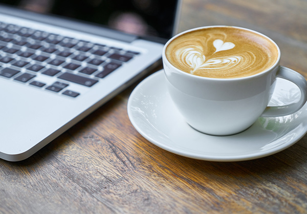A cup of coffee sits near a computer