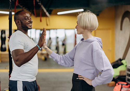 Two people high five after exercising consistently.