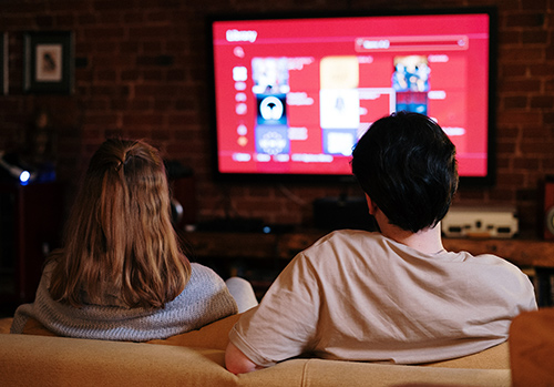 A couple watches a television in their living room.