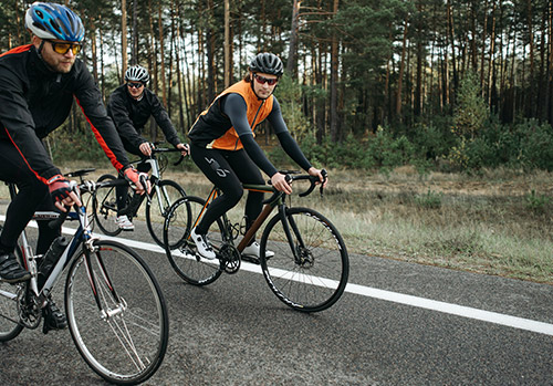 Three people bicycling in woods.