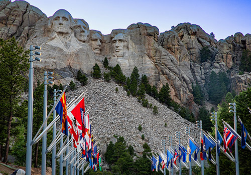 State flags fly in front of Mount Rushmore.