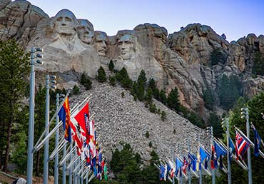 State flags decoratively fly beside each other in front of Mount Rushmore.