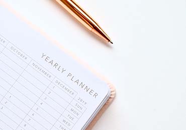 Pen sits by yearly planner on white surface.