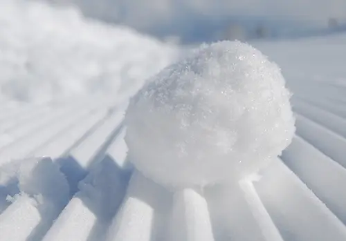 A snowball sits on a bed of snow.