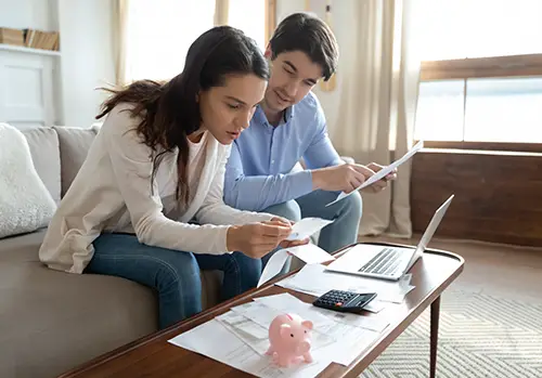 Man and woman sitting in living room looking over reports and paperwork for life insurance.