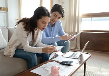 Man and woman sitting in living room looking over reports and paperwork for life insurance.