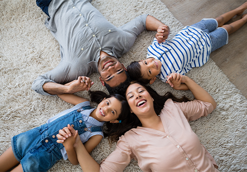 Portrait of happy parents and kids lying on a rug