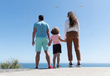 whole life insurance family with father mother and daughter standing on a sunny beach