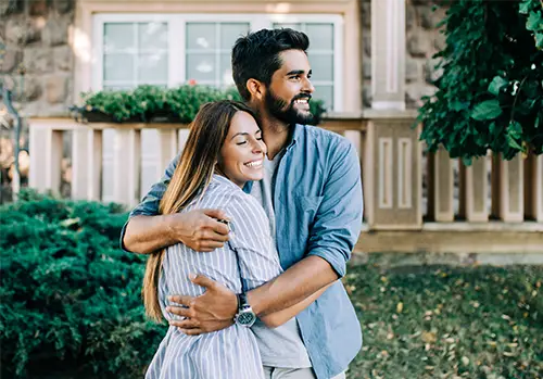 Young Couple Hugging outside of their home