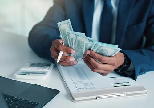 Hands, person and calculate money in office for accounting, audit process and finance checklist. Accountant, cash and laptop with clipboard for tracking expenses, financial management and budgeting