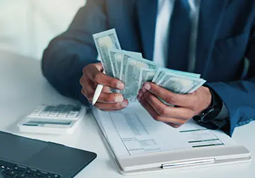 Hands, person and calculate money in office for accounting, audit process and finance checklist. Accountant, cash and laptop with clipboard for tracking expenses, financial management and budgeting